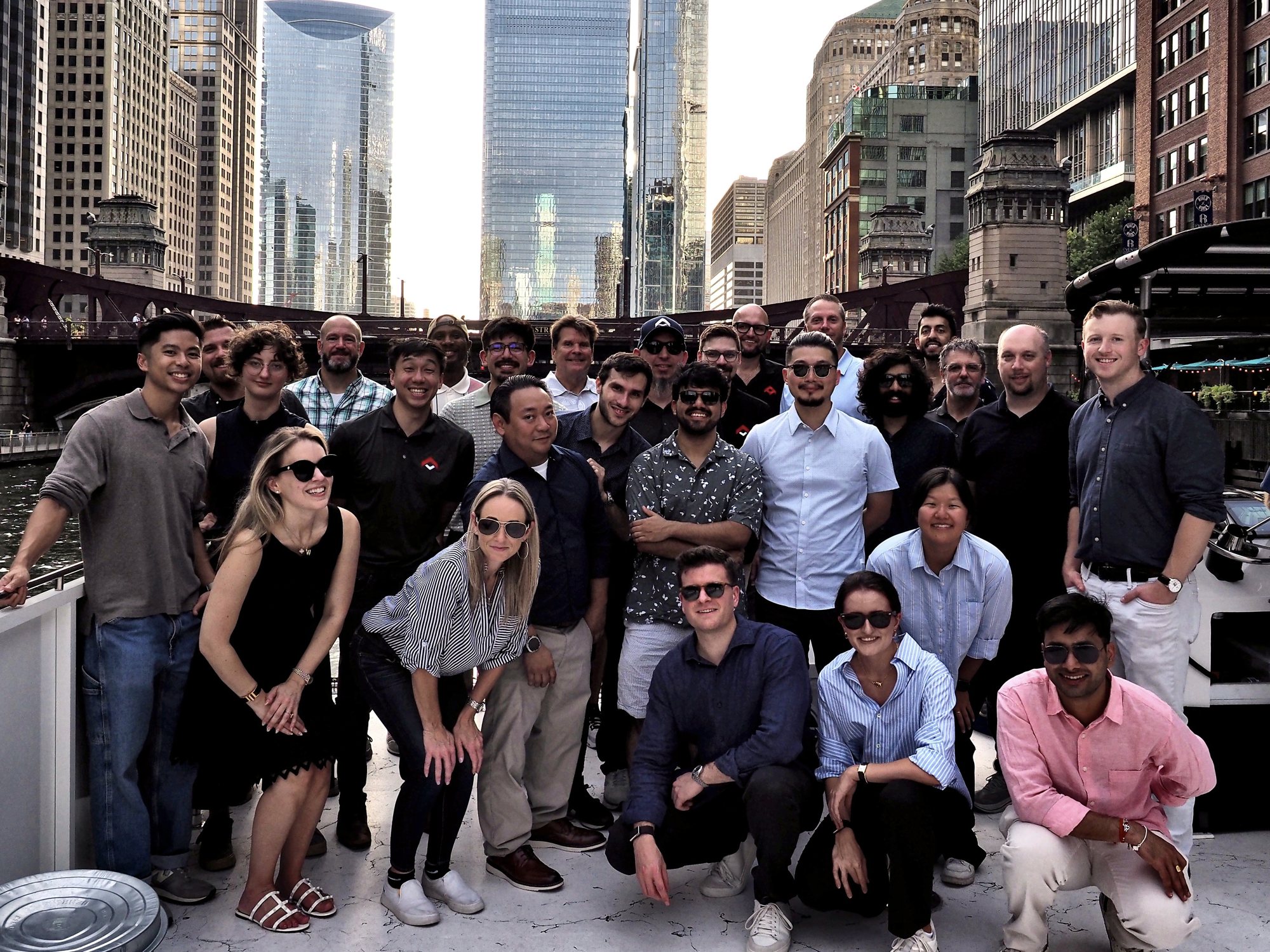 The OneTrack team on a boat on the Chicago River, with the city's towers behind them