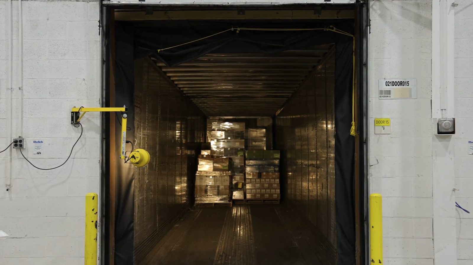 A trailer backed onto a dock door, loaded with wrapped pallets