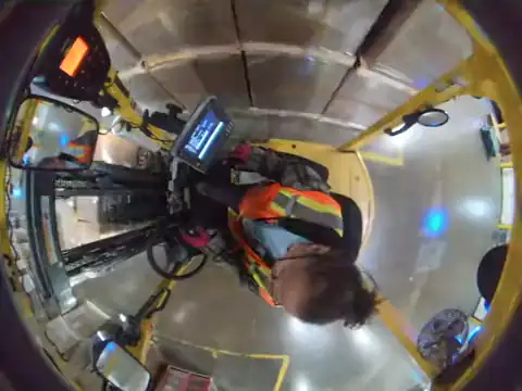 Overhead forklift camera: a sit-down forklift reverses while the operator faces the mast instead of looking behind