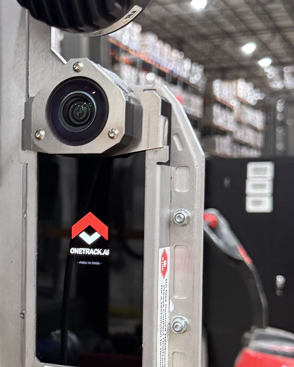 A OneTrack sensor fixed to a lift's mast below the work light, its screen showing the OneTrack mark