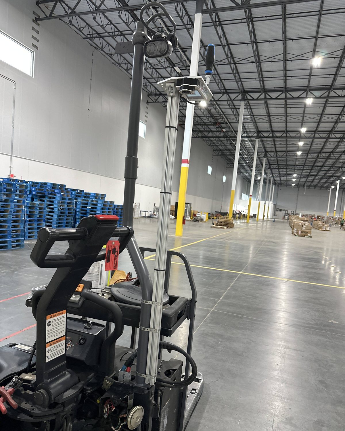 A OneTrack sensor on a post above an electric pallet jack in a large warehouse